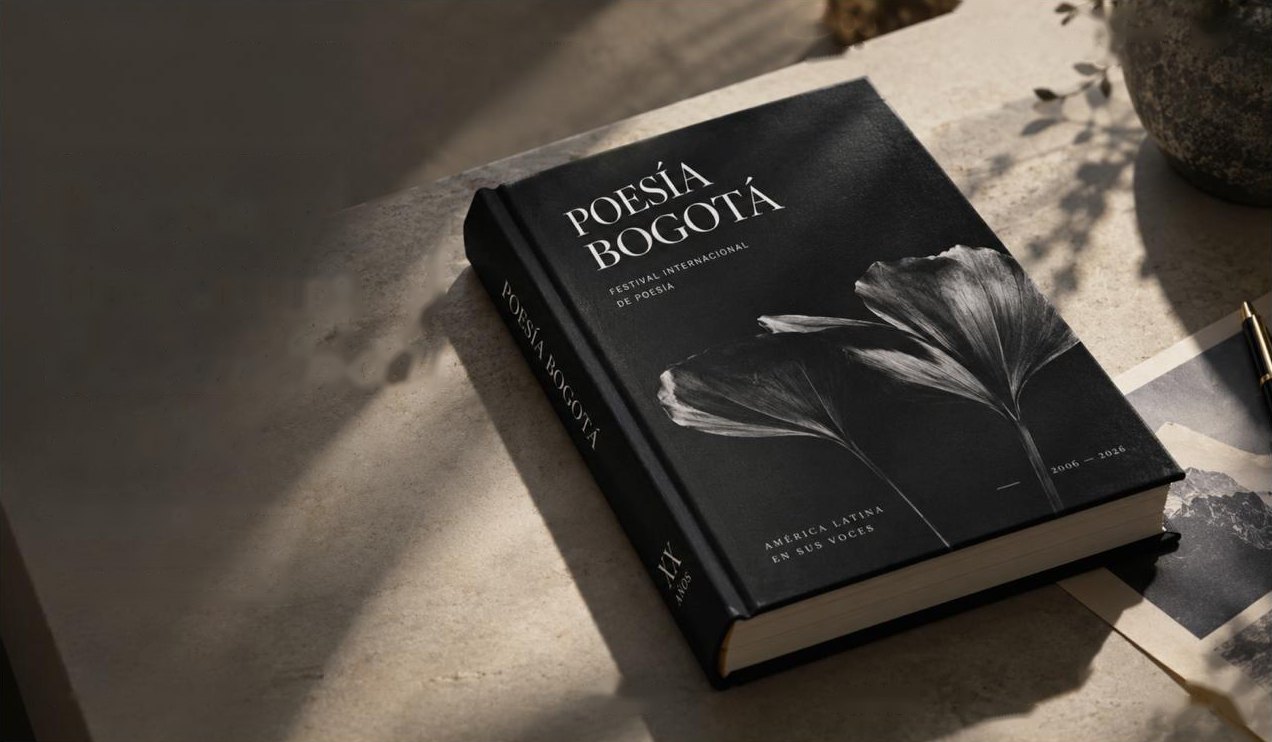 Libro de tapa negra con el título Poesía Bogotá y hojas de ginkgo, sobre una mesa de piedra con luz de tarde